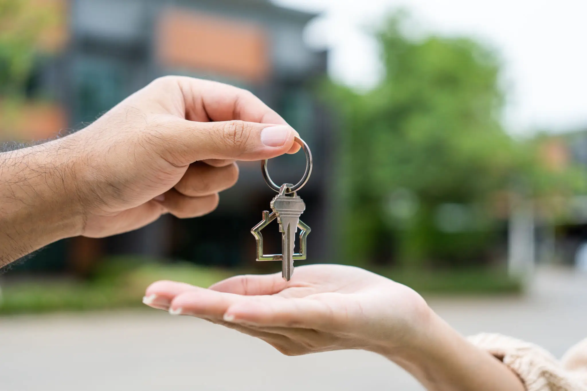 Handing over a house key with a house-shaped keychain.